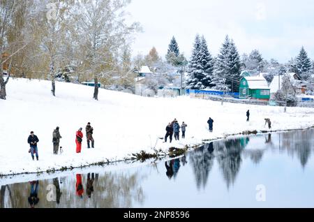 Die Menschen sind Fischer an beiden schneebedeckten Ufern des Sees bei der Konkurrenz in Russland im Wald Stockfoto