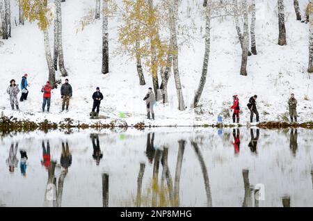 Die Menschen sind Fischer an beiden schneebedeckten Ufern des Sees bei der Konkurrenz in Russland im Wald Stockfoto