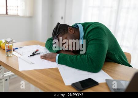 Müder Schwarzer Geschäftsmann Schläft Am Schreibtisch Unter Papers In Office Stockfoto