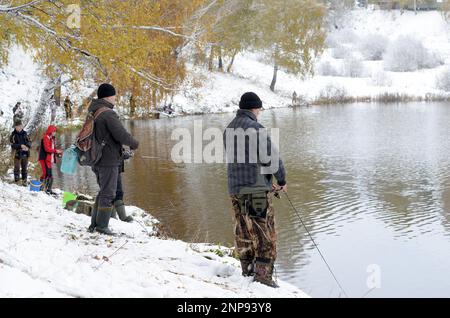 Die Menschen sind Fischer an beiden schneebedeckten Ufern des Sees bei der Konkurrenz in Russland im Wald Stockfoto