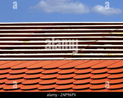 Montage von Dachziegeln aus Biberschwanz auf geneigtem Wohnhausdach. Holzgitterarbeiten. Hellblauer Himmel. Baustoffkonzept Stockfoto