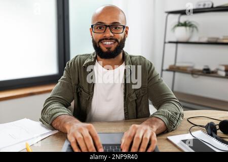 Aufgeregter lateiner mit Brille, der auf der Tastatur eines Laptops tippt und auf den Bildschirm schaut, pov-Aufnahme Stockfoto