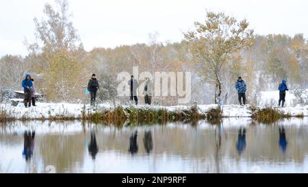 Die Menschen sind Fischer an beiden schneebedeckten Ufern des Sees bei der Konkurrenz in Russland im Wald Stockfoto