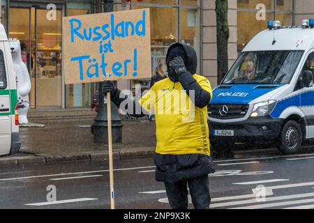 BERLIN - 25. FEBRUAR 2023: Ukrainischer Aktivist mit deutschem Poster "Russland ist ein Verbrecher" vor der russischen Botschaft unter der Linden. Stockfoto