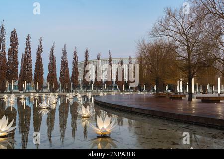 Russland, Krasnodar - 04. Januar 2023: Künstlicher Teich mit blumenförmigen Laternen und Pyramideneichen rund um den Rand des Galitsky-Parks Stockfoto
