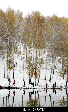 Die Menschen sind Fischer an beiden schneebedeckten Ufern des Sees bei der Konkurrenz in Russland im Wald Stockfoto