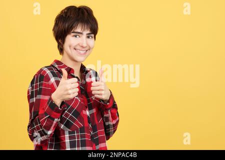 Androgyne Person, die mit erhobenen Daumen ihre Zustimmung gibt Stockfoto