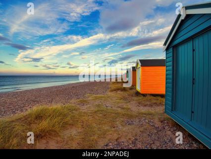 Die wunderschönen, lebhaften Strandhütten am Findhorn in Schottland unter herrlichem blauen Himmel. Stockfoto