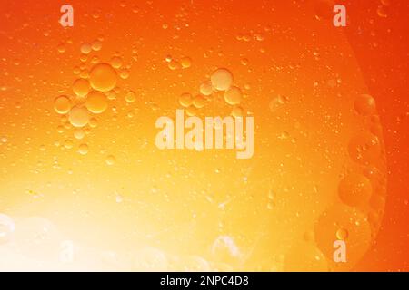 Goldölblasen schließen sich. Kreise des orangefarbenen Wassermakros. Abstrakter, glänzender gelber Hintergrund. Stockfoto