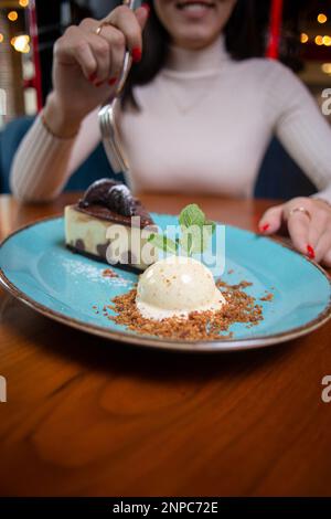 Ein Mädchen ohne Gesicht isst Dessert in einem Café. Stockfoto