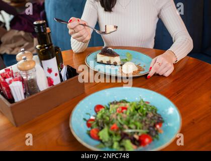 Ein Mädchen ohne Gesicht isst Dessert in einem Café. Stockfoto