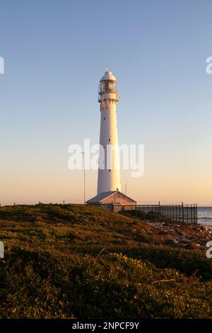 Slangkop Leuchtturm, Kommetjie, Westkap, Südafrika bei Sonnenuntergang von der Küstenpromenade. Der Gusseisenturm wurde 1914 in Betrieb genommen Stockfoto