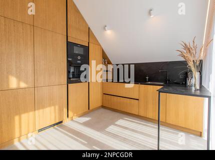 Helle moderne Küche in neuem Luxushaus, Hartholzböden, dunkle Holzschränke. Stockfoto