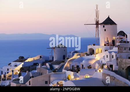 Blick auf eine Windmühle im Dorf Oia bei Sonnenuntergang. Stockfoto