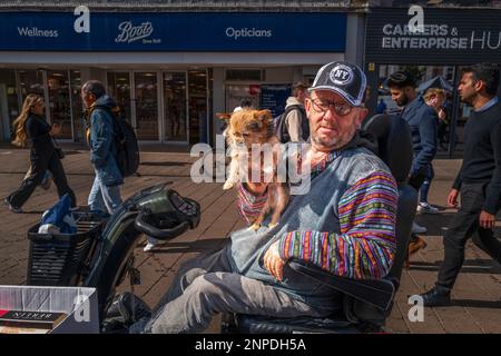 Ein behinderter Mann und sein Hund in einem Roller. Stockfoto