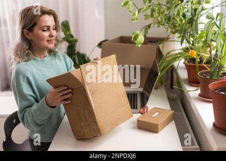 Nahaufnahme eines weiblichen Online-Shops, Inhaber eines kleinen Unternehmens, Unternehmer, der Verpackungspakete nach dem Versand vorbereiteter Versandkarton auf dem Tisch vorbereitet Stockfoto