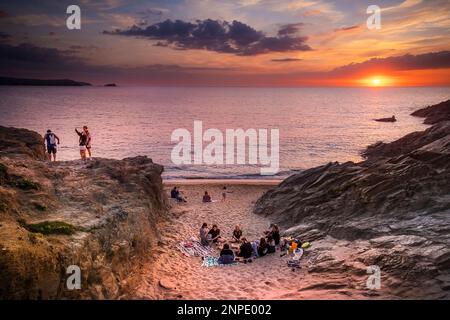 Urlauber genießen einen spektakulären Sonnenuntergang über der Fistral Bay in Newquay in Cornwall in Großbritannien in Europa. Stockfoto