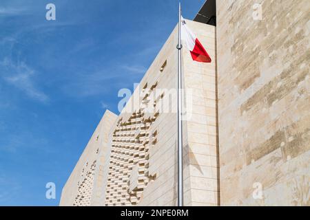 Maltesische Flagge vor dem Parlamentsgebäude, abgebildet unter blauem Himmel in Valetta in Malta. Stockfoto