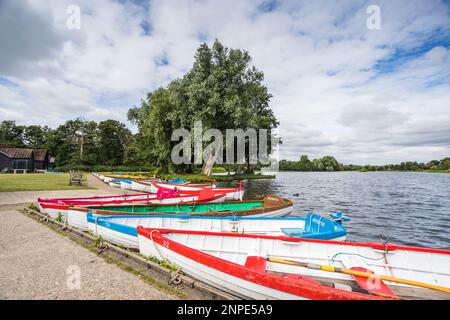 Farbenfrohe Ruderboote am Rand von Thorpeness Mere in Suffolk. Stockfoto