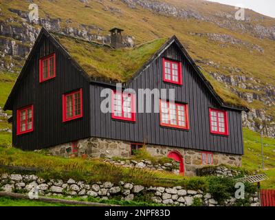 Kirkjubøur, Färöer - Oktober 2020: Typisches Holzrasenhaus mit rotem Fenster auf der Insel Streymoy., Dänemark, Nordeuropa Stockfoto