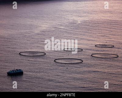 Zauberhafter Sonnenaufgang mit wunderschönen Wolken über dem Meer und der Lachsfarm auf der Färöer Insel. Dänemark. Nordeuropa Stockfoto