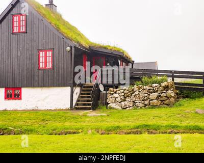 Kirkjubour, Färöer - 2021. Juli: Typisches Färöisches Holzhaus mit roten Fenstern. Nordeuropa Stockfoto