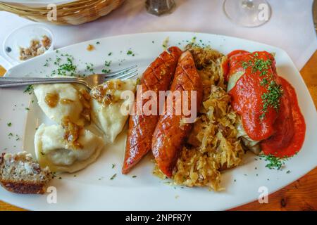 Polnisches Gericht auf einem Teller mit Würstchen, Pierogis, Sauerkraut und Kohl. Stockfoto