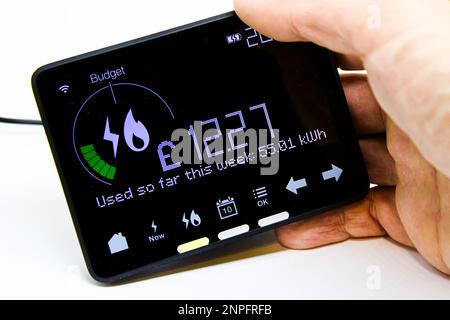 Hand Halten eines intelligenten Zählermonitors, der den Energieverbrauch für Gas und Strom in der aktuellen Woche in Verbindung mit den Kosten in Pfund Sterling anzeigt Stockfoto