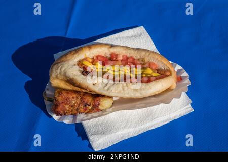 Nahaufnahme von Sonoran Hot Dog auf blauem Tisch. Sonoran Hot Dogs sind eine Spezialität des Bundesstaates Sonora in Mexiko und im Gebiet von Tucson in den USA. Stockfoto