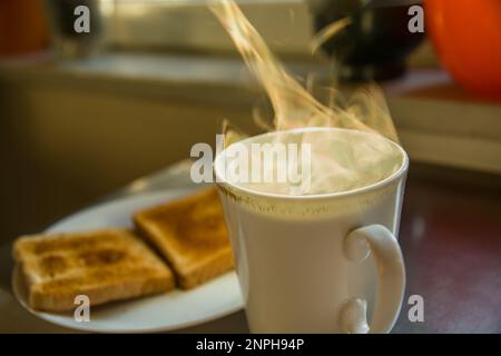 Dampf aus heißem Tee und zwei Toasts auf einem Teller, Blick auf den Morgen Stockfoto