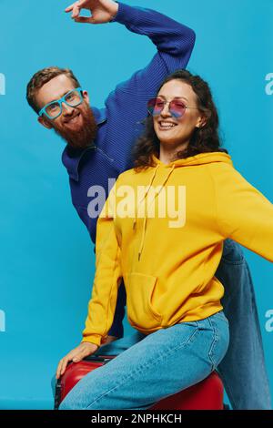 Frau und Mann lächeln auf dem Koffer mit rotem Kofferlächeln auf blauem Hintergrund, packen für die Reise, Familienurlaub. Stockfoto