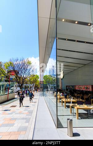 Äußere der Glasfassade der Apple Store in Omotesando, Tokio. Tagsüber, Blick entlang Gebäude angezeigt. Pflaster mit Menschen zu Fuß. Stockfoto