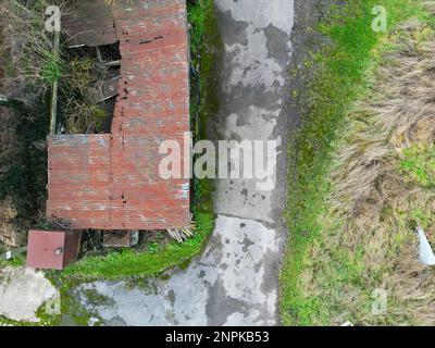 Blick von oben auf heruntergekommene Gebäude auf einem Bauernhof. Unten links befindet sich ein Dieseltank. Stockfoto