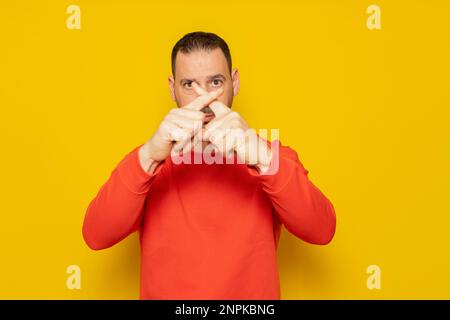 Hispanischer Mann mit Bart über gelbem Hintergrund Ausdruck der Zurückweisung, der seine Finger kreuzt und ein Abstoßungszeichen macht, ist wütend auf die Stockfoto