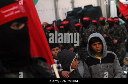 Rafah, Gaza. 26. Februar 2023. Palästinensische Jungen betrachten maskierte Kämpfer der Demokratischen Front für die Befreiung Palästinas (DFLP) bei einer Parade in Rafah-Stadt im südlichen Gazastreifen am Sonntag, den 26. Februar 2023, zur Unterstützung des Westjordanlands und der Palästinenser in israelischen Gefängnissen und gegen den palästinensisch-israelischen Gipfel in Akaba. Foto: Ismael Mohamad/UPI Credit: UPI/Alamy Live News Stockfoto