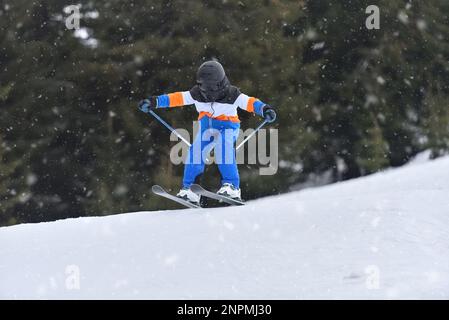 Fantastischer Wintersport: 10-jähriger Skifahrer, der durch die Luft ragt Stockfoto