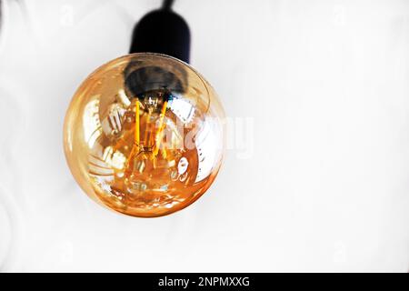 Nahaufnahme einer Glühlampe an einer Wand, die mit Strom, Strom, Stockfoto