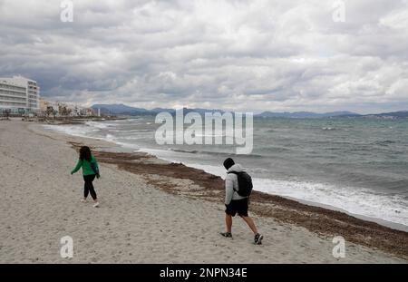 Santa Margalida, Spanien. 26. Februar 2023. Leute, die am Strand von Can Picafort spazieren gehen. In den nächsten Tagen wird mit Regenwetter und sinkenden Temperaturen gerechnet. Kredit: Clara Margais/dpa/Alamy Live News Stockfoto