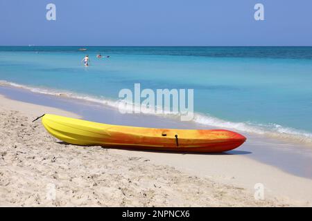 Gelbes rotes Kajak auf dem Sand des Ozeanstrands. Tropische Küste mit Menschen, die im blauen Wasser schwimmen Stockfoto