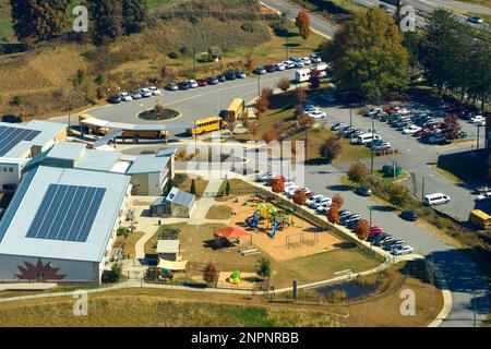 Dach des amerikanischen Schulgebäudes mit Photovoltaik-Solarpaneelen für die Stromerzeugung. Konzept für erneuerbare Energien. Stockfoto