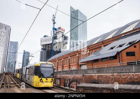 Eine gelbe und graue Metrolink-Straßenbahn, die im Februar 2023 von Deansgate ins Stadtzentrum von Manchester fährt. Stockfoto