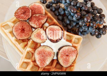 Wiener Waffeln mit Feigen und schwarzen Trauben zu Hause und im Restaurant. Gesundes, gesundes Frühstück für Vegetarier. Hochwertiges Foto Stockfoto