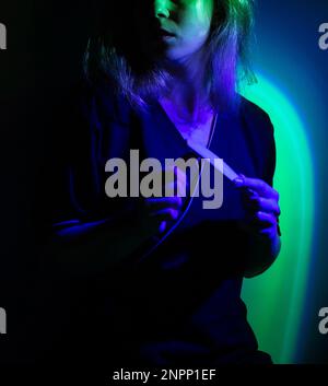 Maniküre mit Nagelfeilen in den Händen auf farbenfrohem Neonhintergrund. Ein Mädchen in einer professionellen Maniküre trägt Maniküre-Werkzeuge in Neon Stockfoto