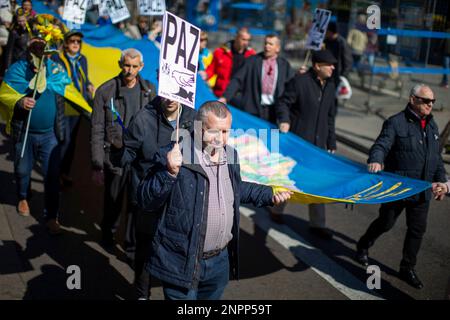 Madrid, Spanien. 26. Februar 2023. Demonstranten halten während eines marsches durch die Straßen von Madrid eine riesige Flagge, organisiert von ukrainischen Verbänden in Madrid, um ein Ende des Krieges am ersten Jahrestag des Beginns der russischen Invasion in der Ukraine zu fordern. Kredit: SOPA Images Limited/Alamy Live News Stockfoto