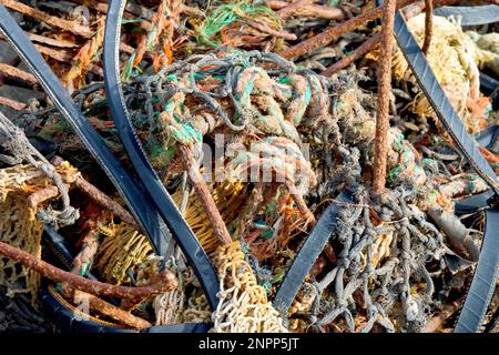 Nahaufnahme des verwickelten Chaos aus rostfreiem Eisen, Gummibändern und Nylonseilen und Netztuch eines alten Krabbentopfs oder Creels, das an einem Strand angespült wurde. Stockfoto