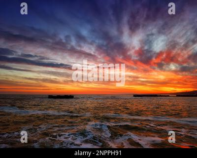 Ein wunderbarer Sonnenuntergang an der Küste des Ozeans in Orange-Rot-Tönen Stockfoto