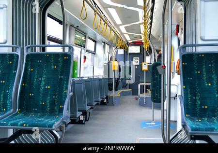 Innengestaltung eines modernen Busses für den Personenverkehr in der Stadt. Ein Bus mit blauen Sitzen und gelben Garanten. Öffentliche Verkehrsmittel. Stockfoto