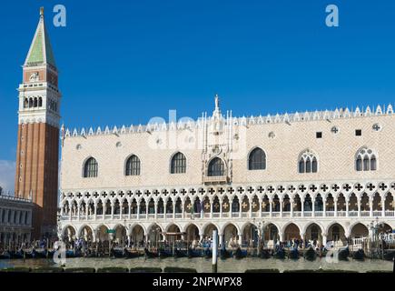 Dogenpalast mit Glockenturm und Gondel in St. Markusplatz an einem sonnigen Tag in Venedig, Venetien in Italien. Stockfoto