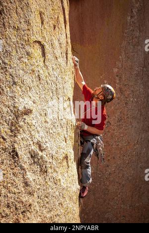 Männlicher Erwachsener steigt eine steile Mauer in den Dragoon's Mountains, Arizona, hinauf Stockfoto