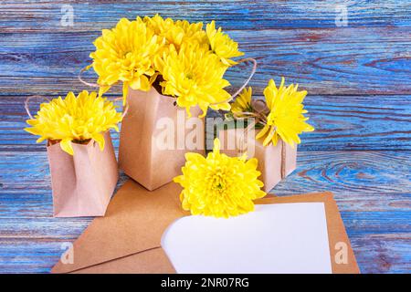 Gelbe Blüten einer Chrysantheme mit Geschenken und Platz für Grußtext, selektiver Fokus. Stillleben auf einem hölzernen Hintergrund Stockfoto